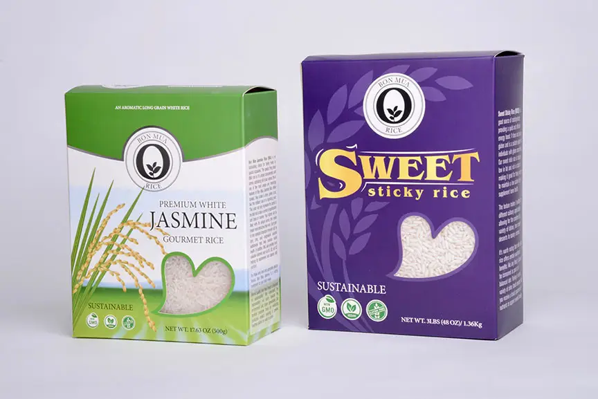 A green Bon Mua jasmine rice box and a purple Bon Mua sweet sticky rice box standing side by side on a pale background.