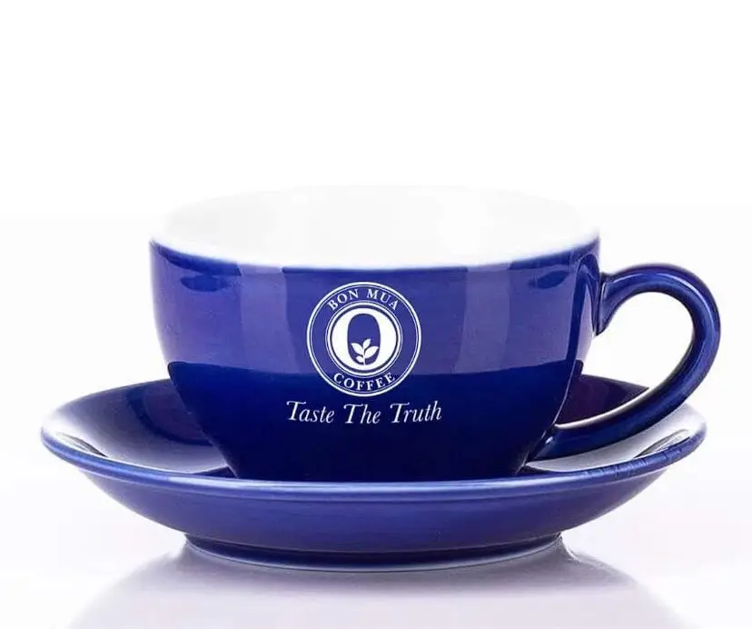 A cobalt-blue ceramic cup and saucer with the white Bon Mua Coffee logo and the words Taste The Truth, on a white background.