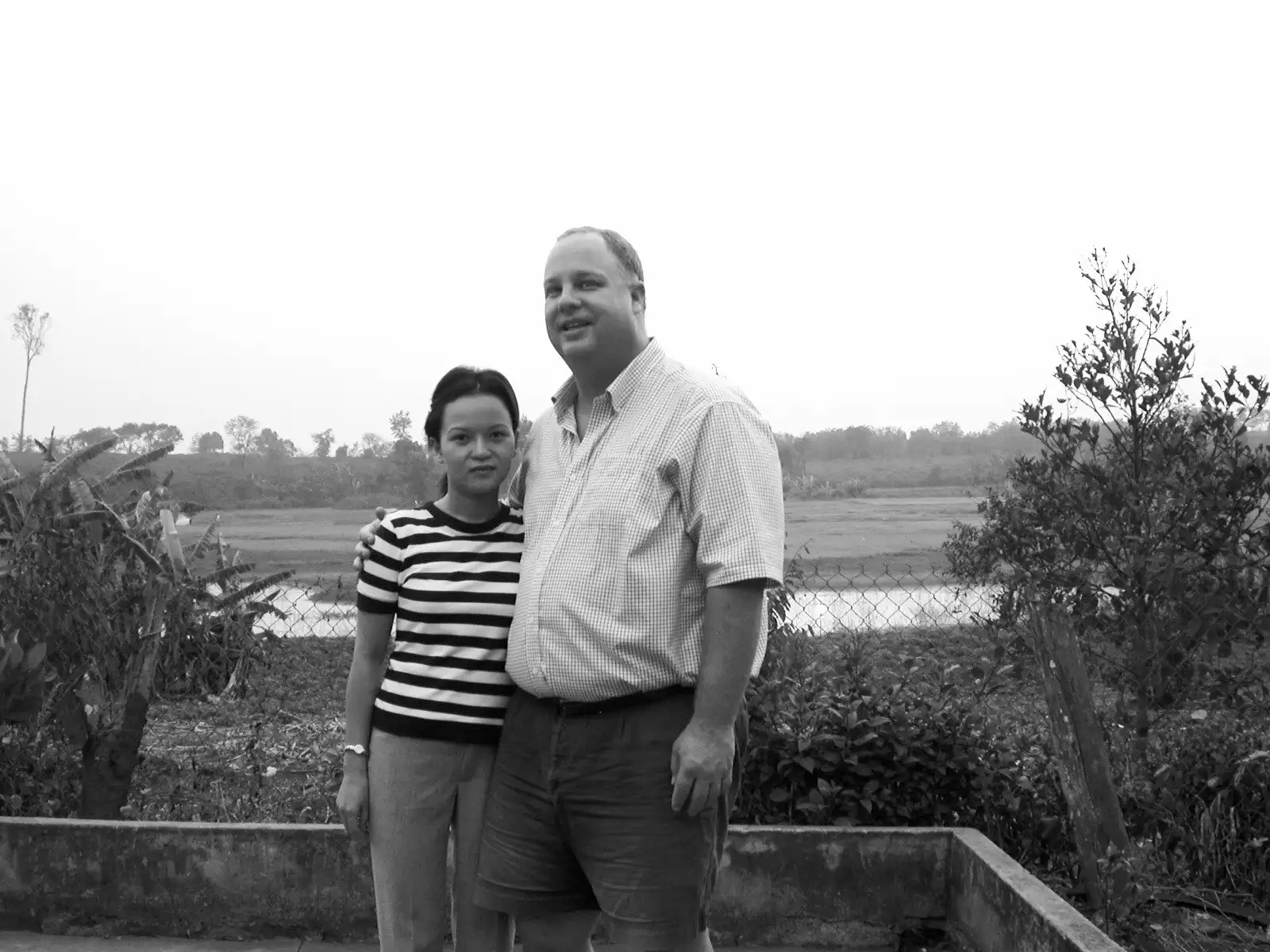 Founder Lan Marberry and John Marberry standing arm in arm beside a rural rice field in Vietnam.
