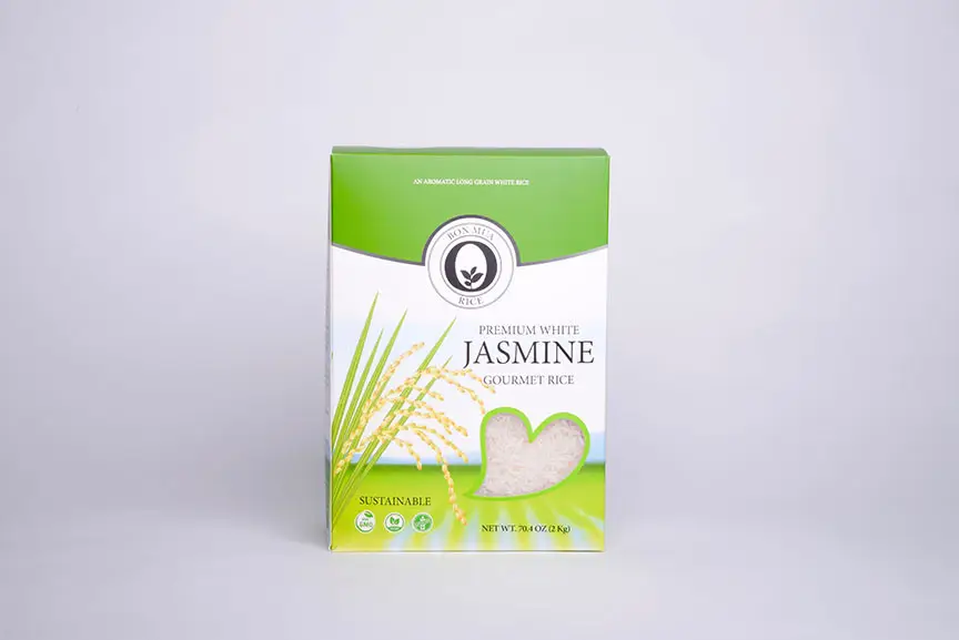 A green-and-white Bon Mua Premium White Jasmine Gourmet Rice box with a rice-plant illustration and white rice grains shown in a heart-shaped window, on a pale background.
