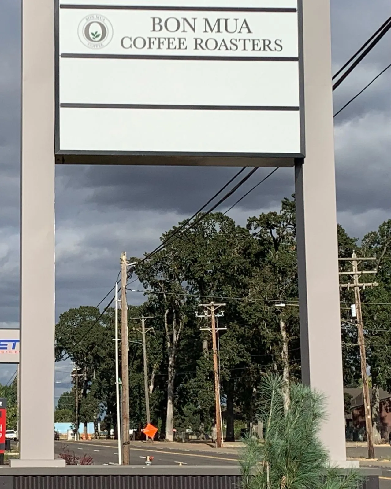 A tall roadside pylon sign reading Bon Mua Coffee Roasters with the O logo, against a cloudy Salem sky.